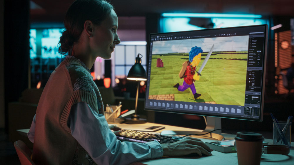 Mladá žena sedící u stolního počítače a hrající PC hru_02