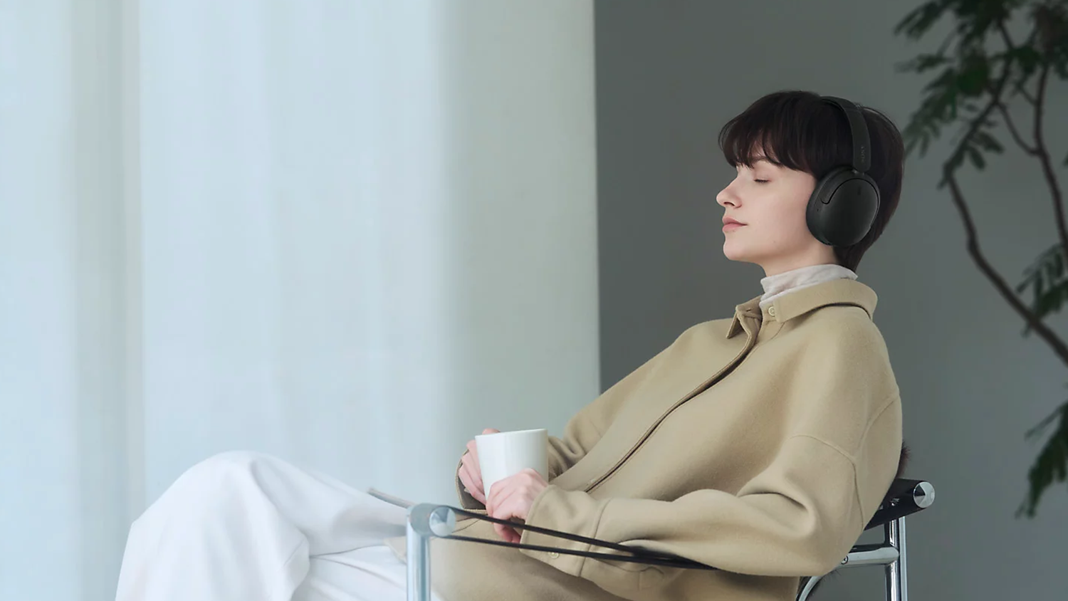 Sediaca žena s bezdr&ocirc;tov&yacute;mi sl&uacute;chadlami Sony WH-CH730N