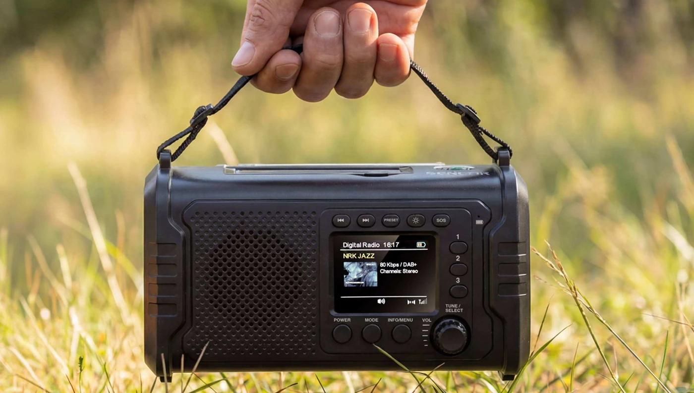Prenosné rádio SENCOR SRD 1090 držané za pútko rukou v tráve