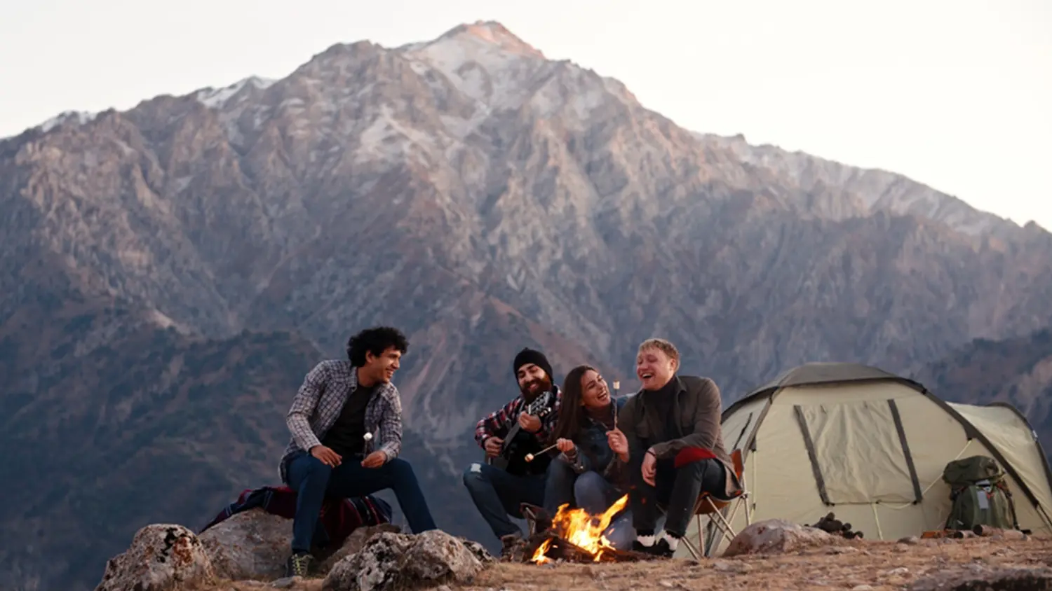 Skupina lid&iacute; poslouch&aacute; hudbu u t&aacute;bor&aacute;ku.