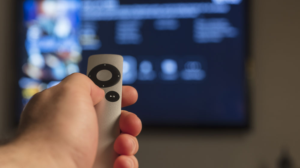 Člověk mířící Apple Remote na televizi_04
