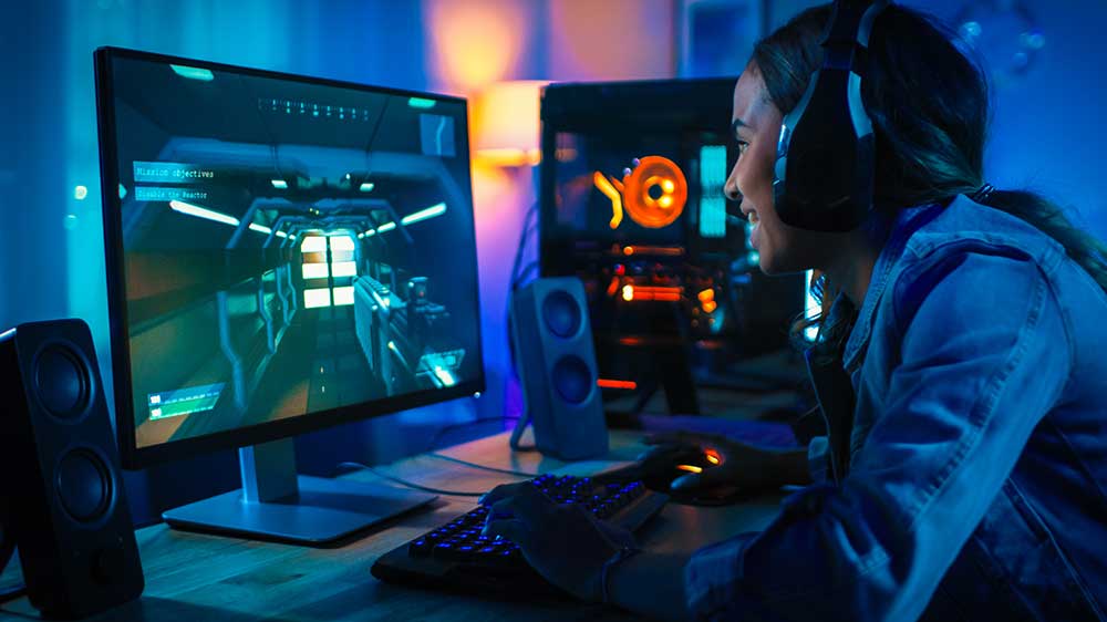 Mladá žena hraje akční hru na počítači a má nasazená sluchátka_03
