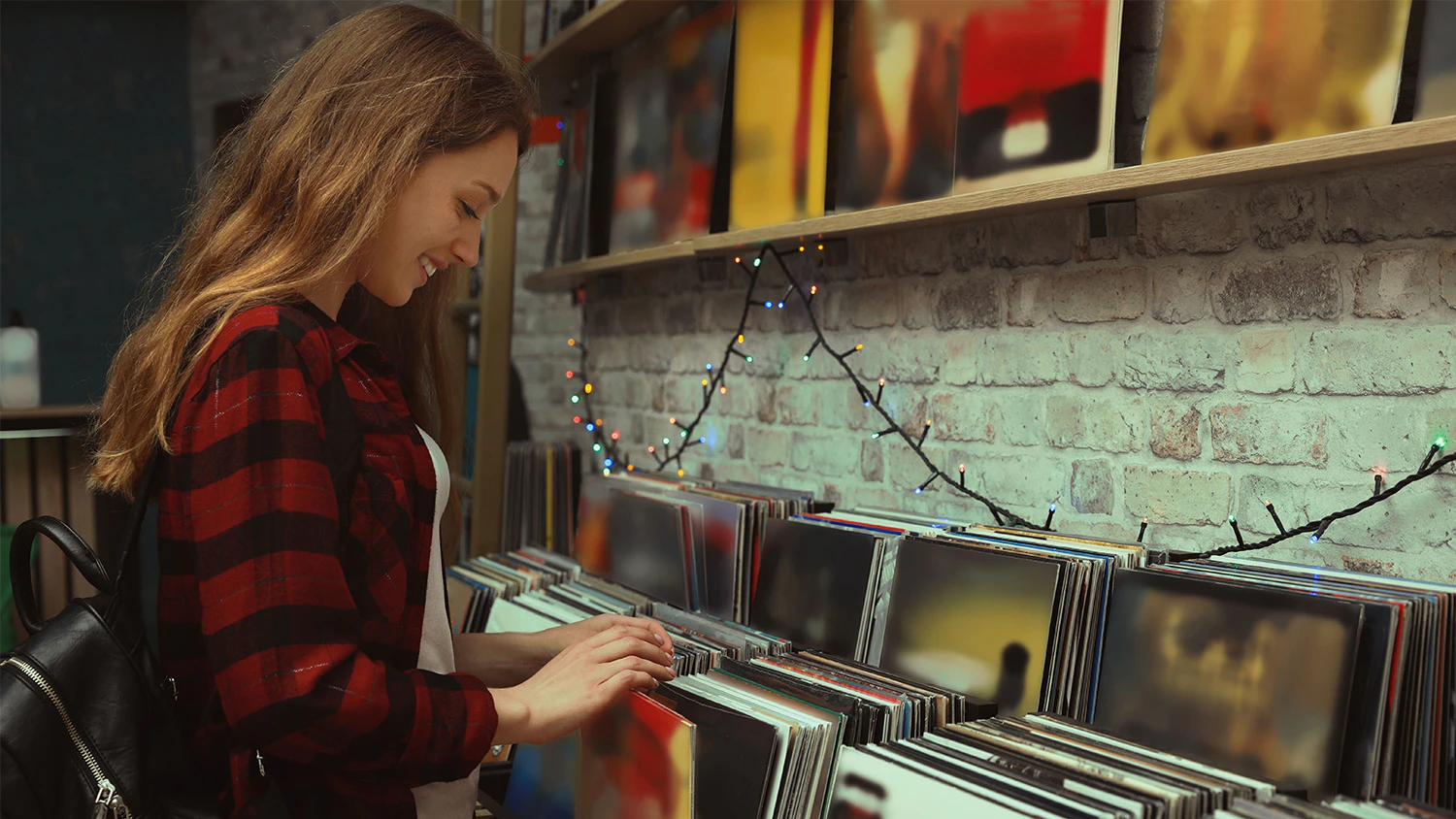 Žena si s úsmevom vyberá vinylové platne v obchode