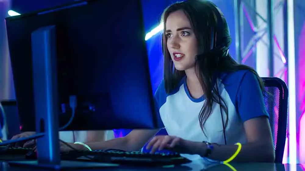 Mladá žena ponořená do PC hry s nasazenými sluchátky na hlavě_04