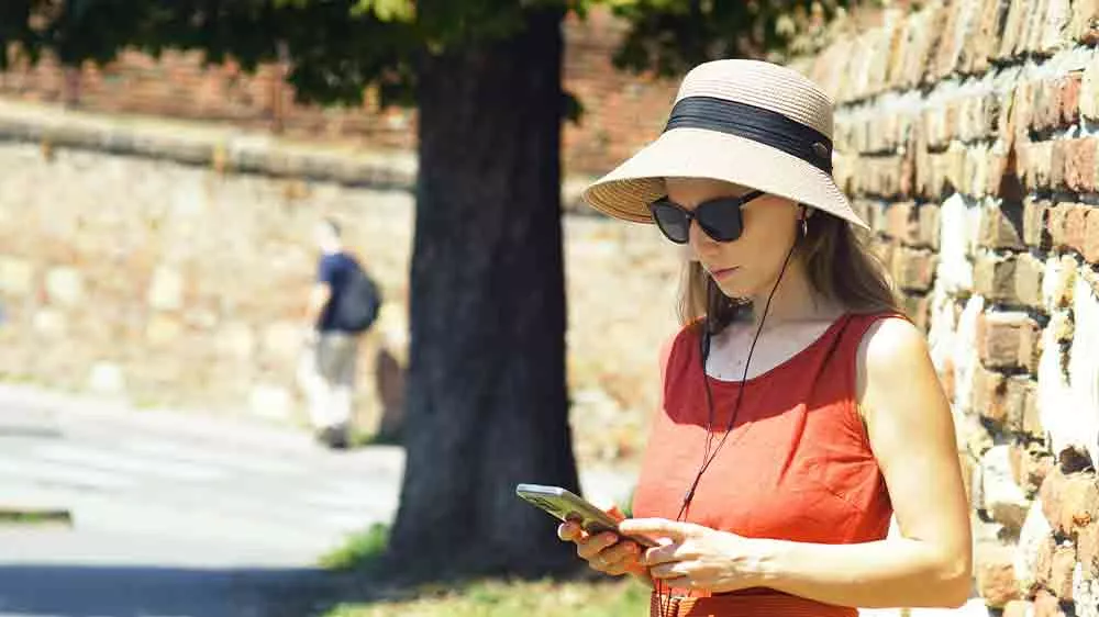 Žena ve městě se sluchátky připojenými k mobilu_02