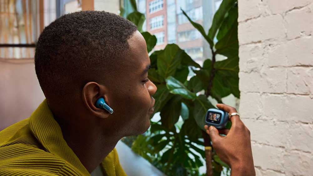 Muž ovládá sluchátka JBL Live Flex 3 přes dotykový displej na pouzdře_03