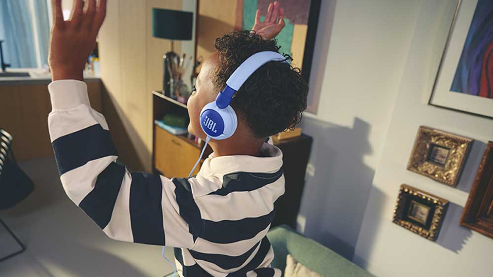 Veselý chlapec tančí při poslechu hudby ze sluchátek JBL JR320_02