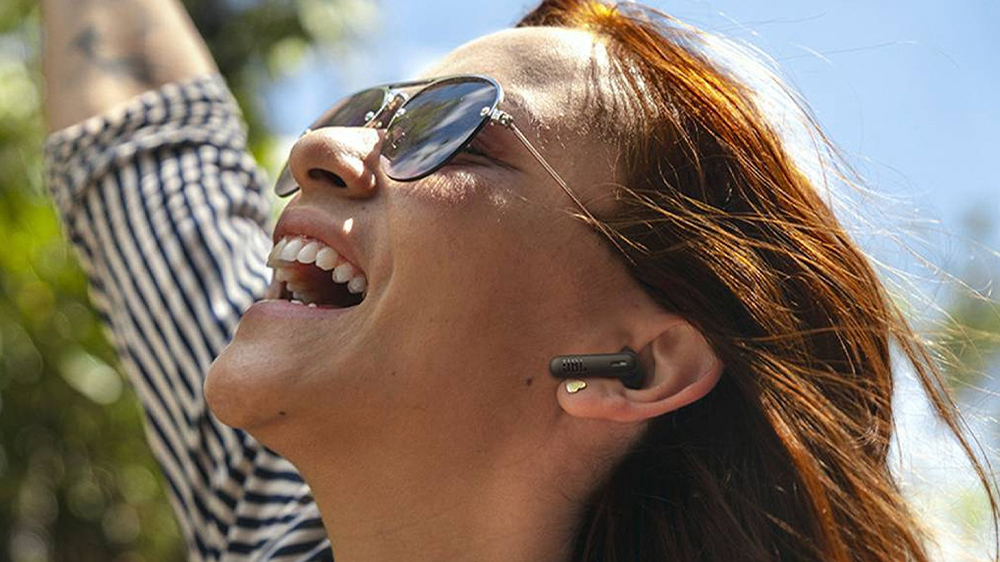 Mladá šťastná žena s bezdrátovými sluchátky JBL Wave Beam 2_44