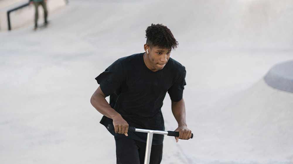 Chlapec se sluchátky JBL Wave Flex White na koloběžce_03