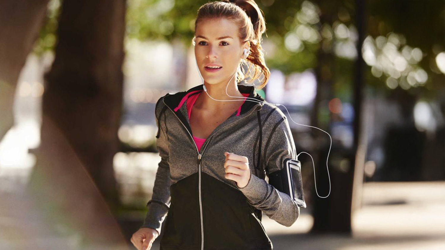 Žena běží v parku se sluchátky JBL Endurance Run 3C