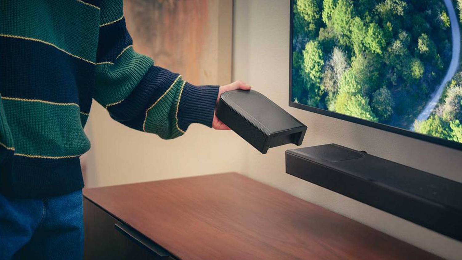Muž berie jeden reproduktor soundbaru JBL