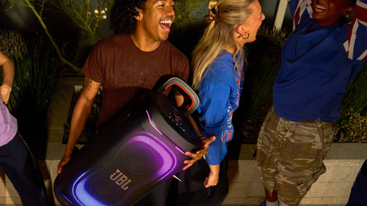 Bav&iacute;c&iacute; se lid&eacute; a muž s reproduktorem JBL PartyBox 330 v n&aacute;ruč&iacute;