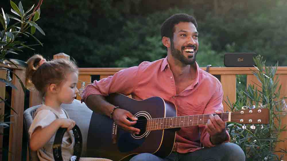 Muž hraj&iacute;c&iacute; na kytaru u reproduktoru