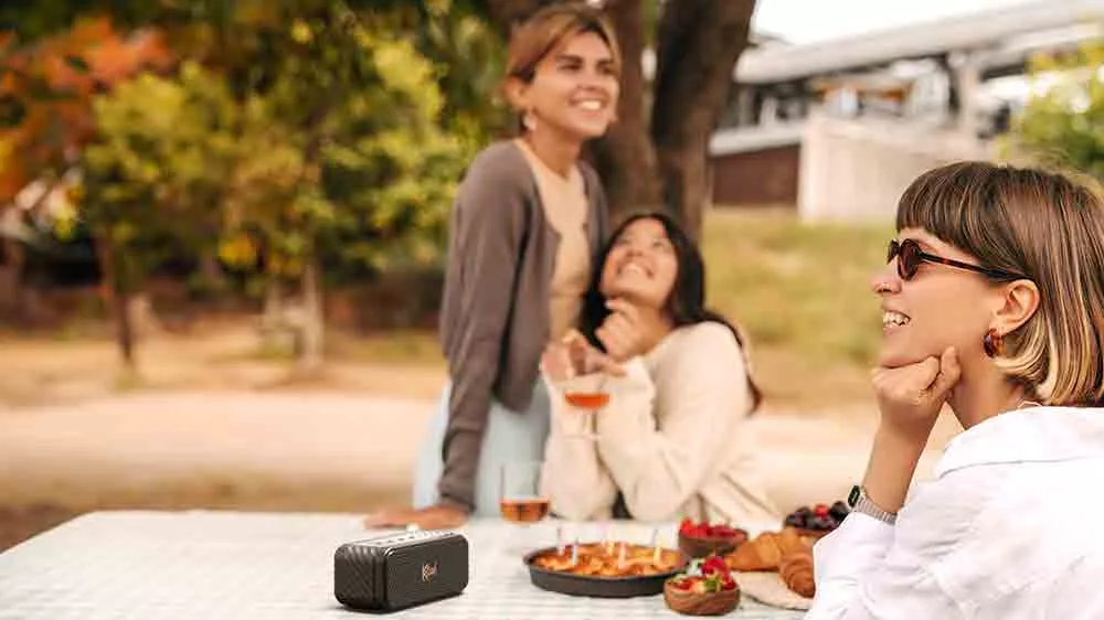 Lid&eacute; sed&iacute;c&iacute; u piknikov&eacute;ho stolu s reproduktorem Klipsch Nashville