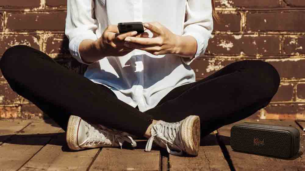 Člověk s telefonem sed&iacute;c&iacute; vedle reproduktoru