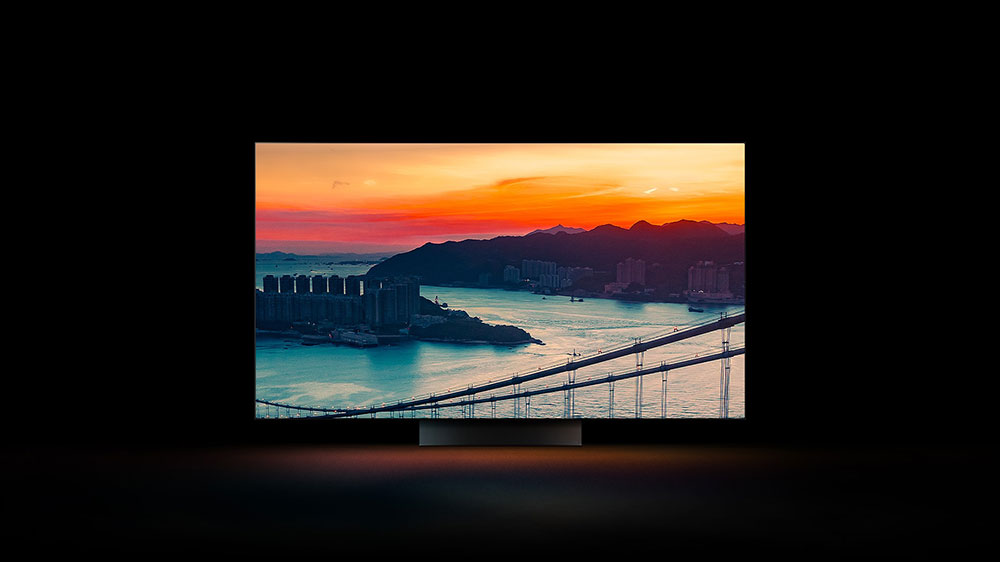 Moře, město a západ slunce na obrazovce OLED televize LG OLED77C21LA vystupující ze tmy