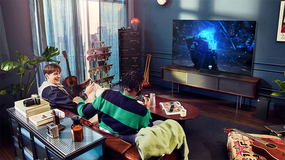 Dva mladící na pohovce se baví při hraní počítačové hry na OLED Televizi LG OLED65A23LA