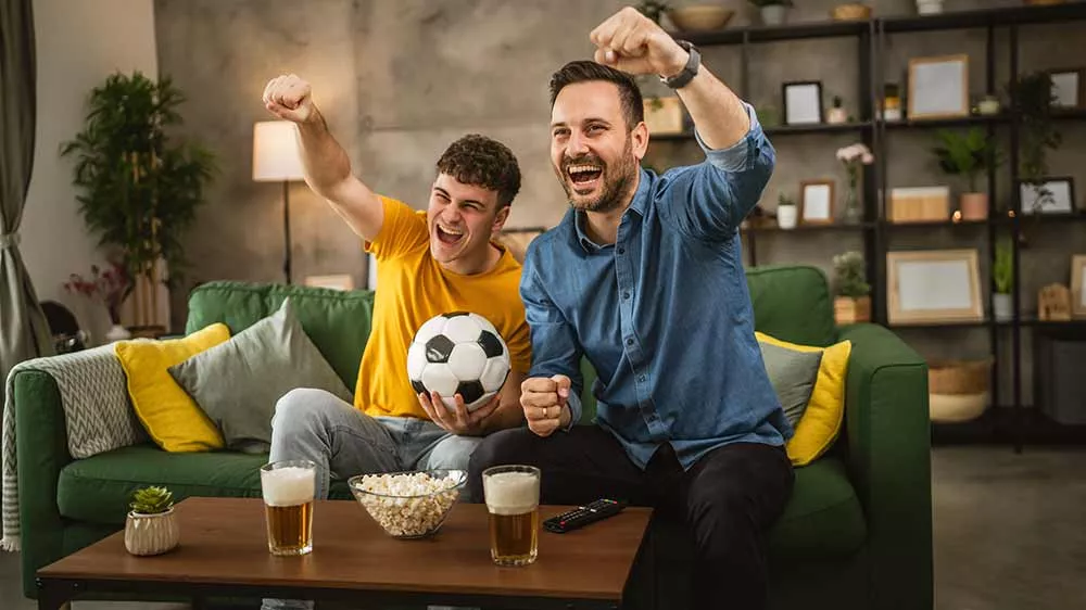 Dva muži sleduj&iacute;c&iacute; fotbalov&yacute; z&aacute;pas v televizi_03
