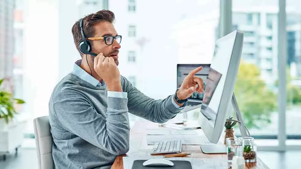 Muž se sluchátky pracuje u monitoru počítače_02