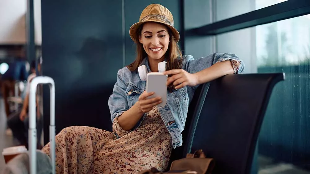 Mladá žena s bílými sluchátky kolem krku a mobilem_02