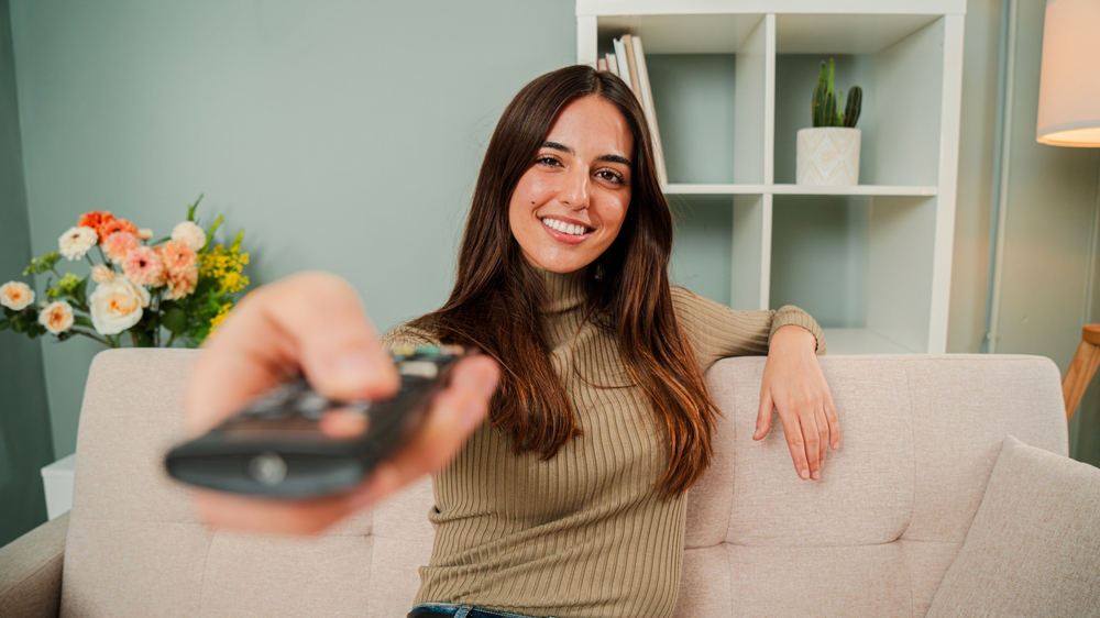 Žena sedící na pohovce mířící dálkovým ovladačem_03
