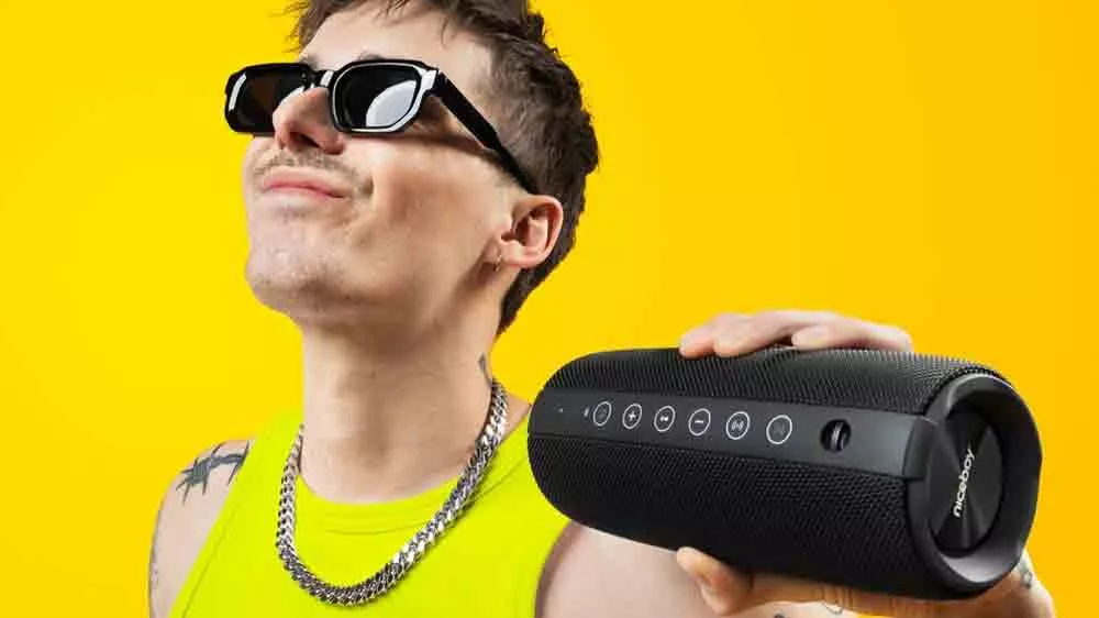 Mladý, usmievajúci sa muž drží v ruke reproduktor Niceboy Titan 4