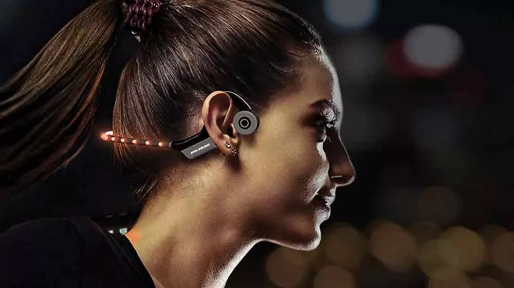 Žena je venku ve tmě a m&aacute; nasazen&aacute; sluch&aacute;tka OPN Sound Dashlyte s LED světly_03