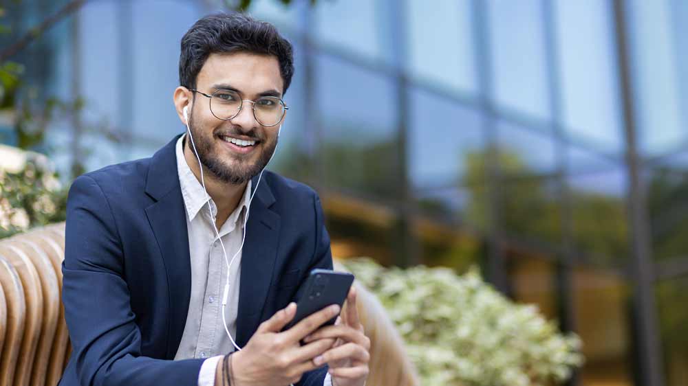 Muž s kabelov&yacute;mi b&iacute;l&yacute;mi sluch&aacute;tky poslouch&aacute; hudbu z mobilu_02