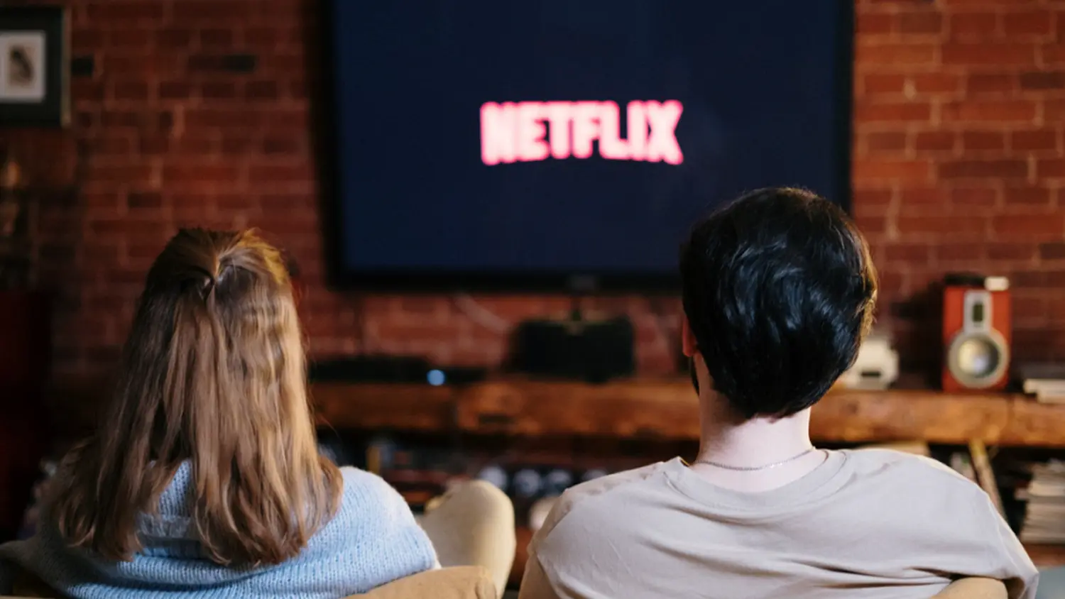 Pár sedí na sedačce a dívá se na Netflix v televizi