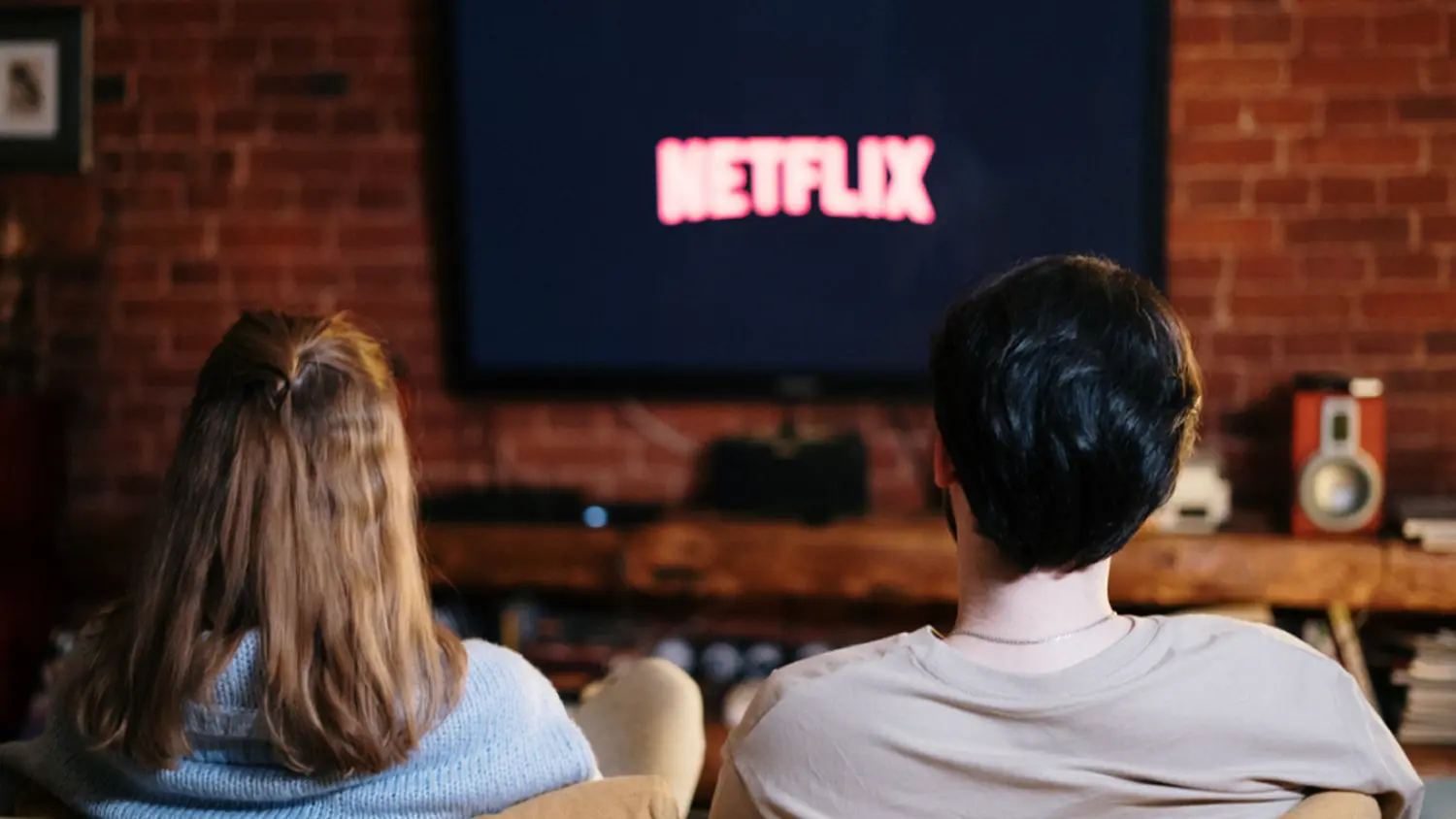 Pár sedí na gauči a pozerá Netflix v televízore