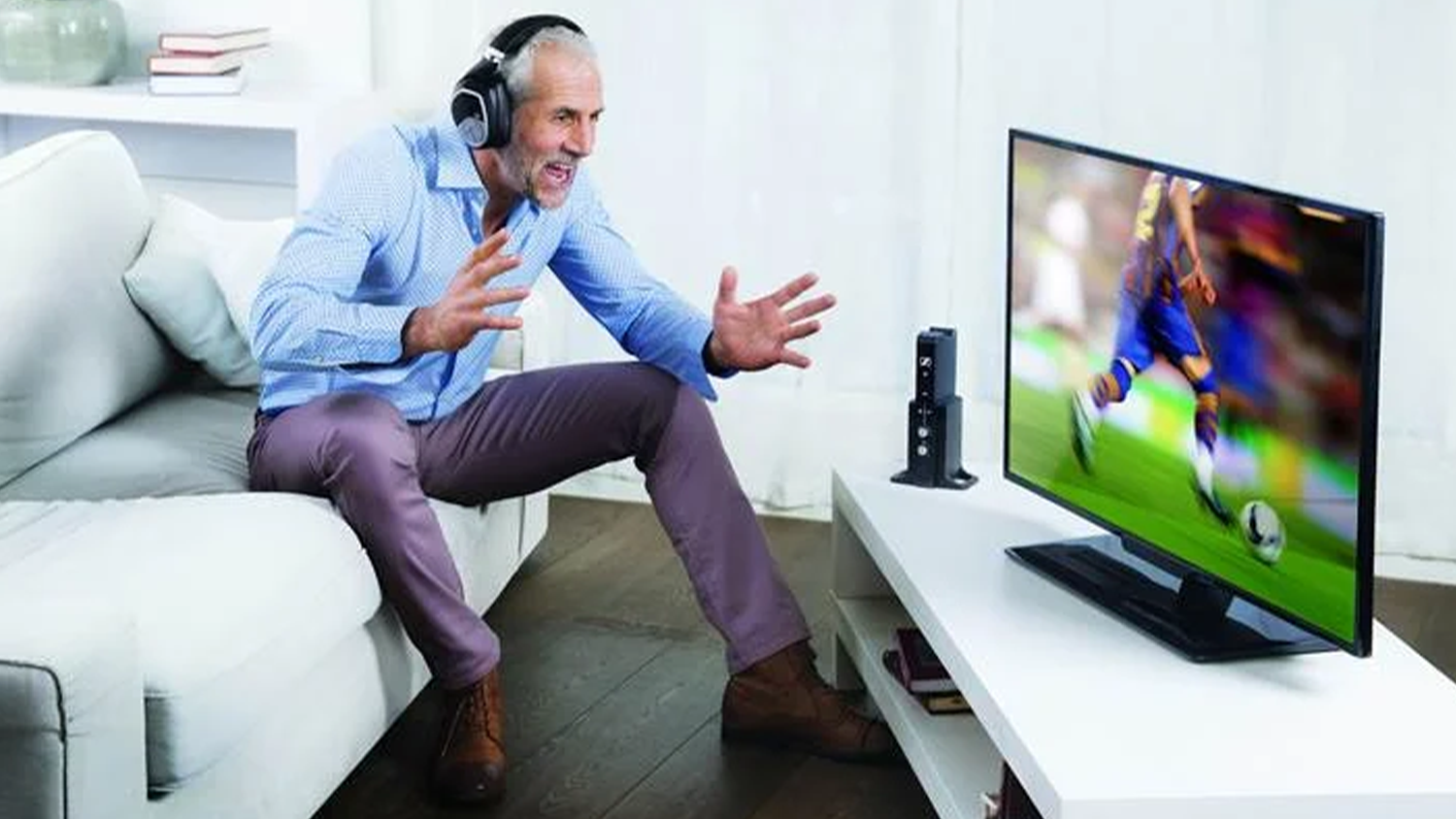 Muž u televize se sluch&aacute;tky Sennheiser RS 195