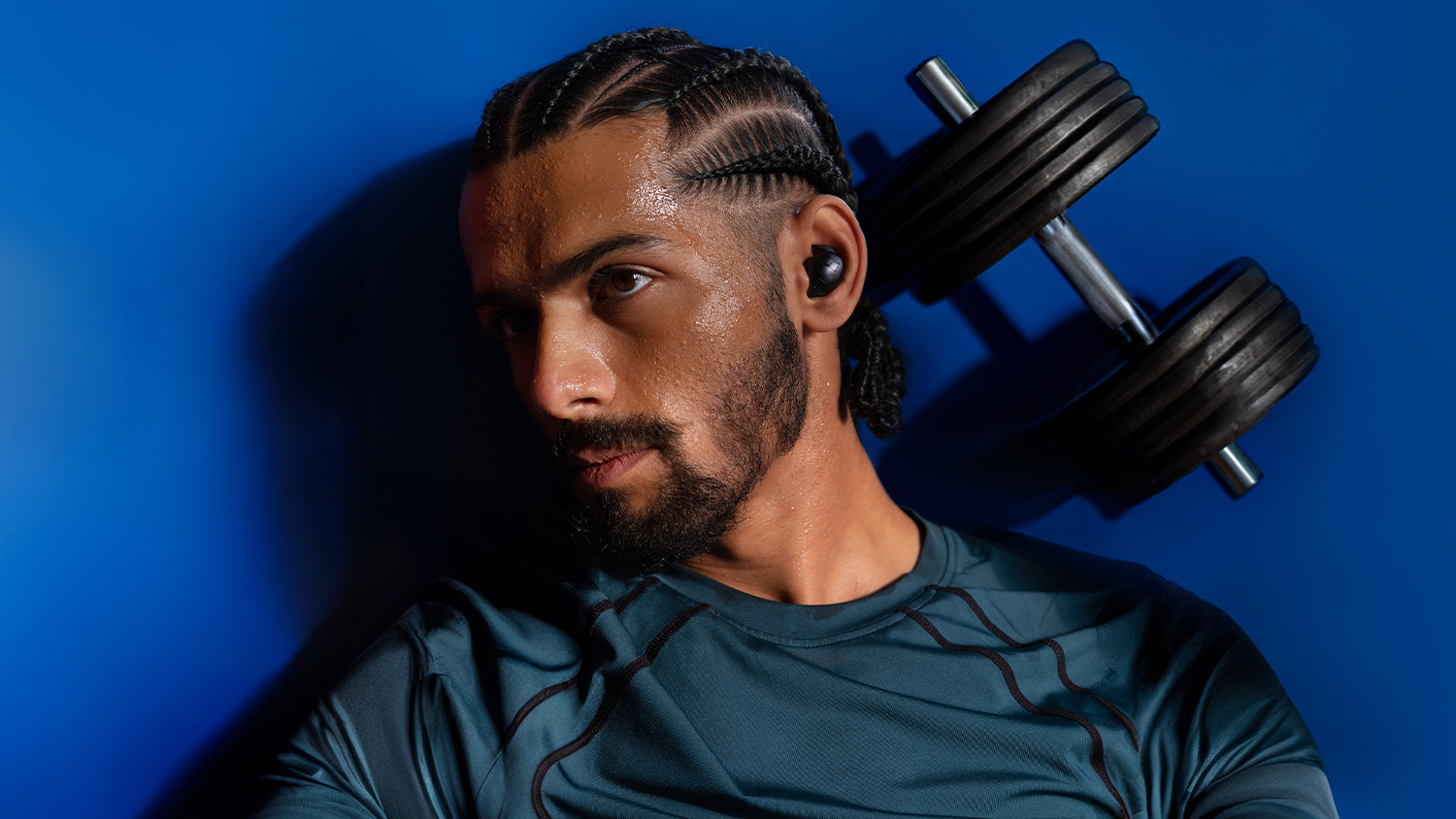 Muž s činkou a slúchadlami Sennheiser MOMENTUM Sport