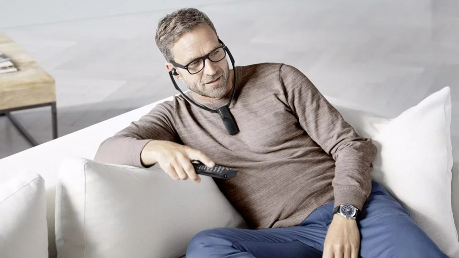 Muž na pohovce s nasazeným systémem Sennheiser SET 880