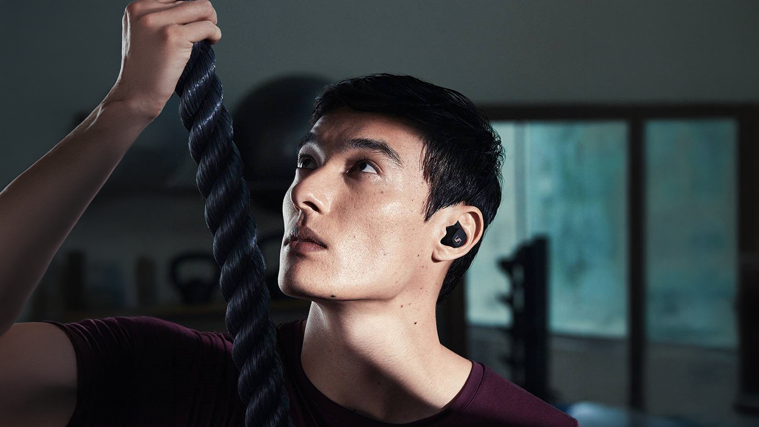 Muž v posilňovni so sl&uacute;chadlami Sennheiser SPORT True Wireless