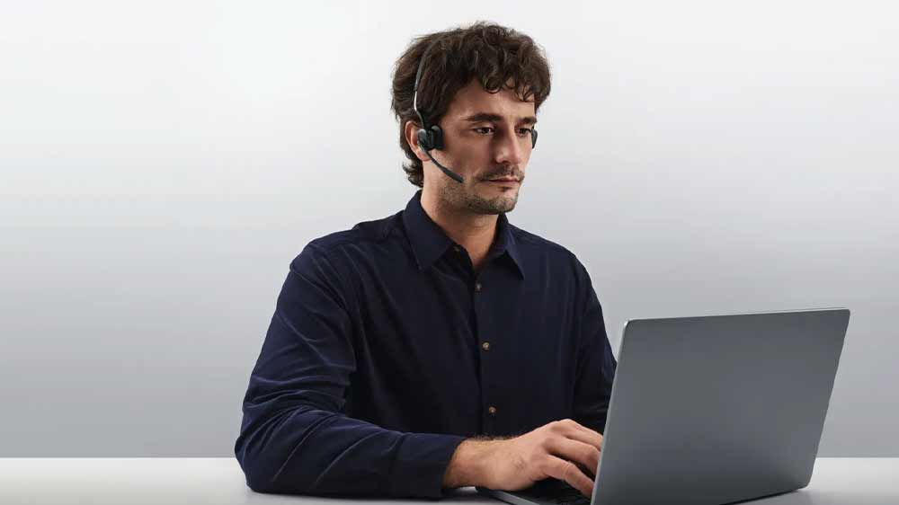 Muž so slúchadlami Shokz OpenMeet pracujúci na notebooku_04