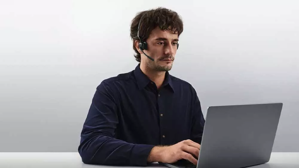 Muž se sluch&aacute;tky Shokz OpenMeet pracuj&iacute;c&iacute; na notebooku_04