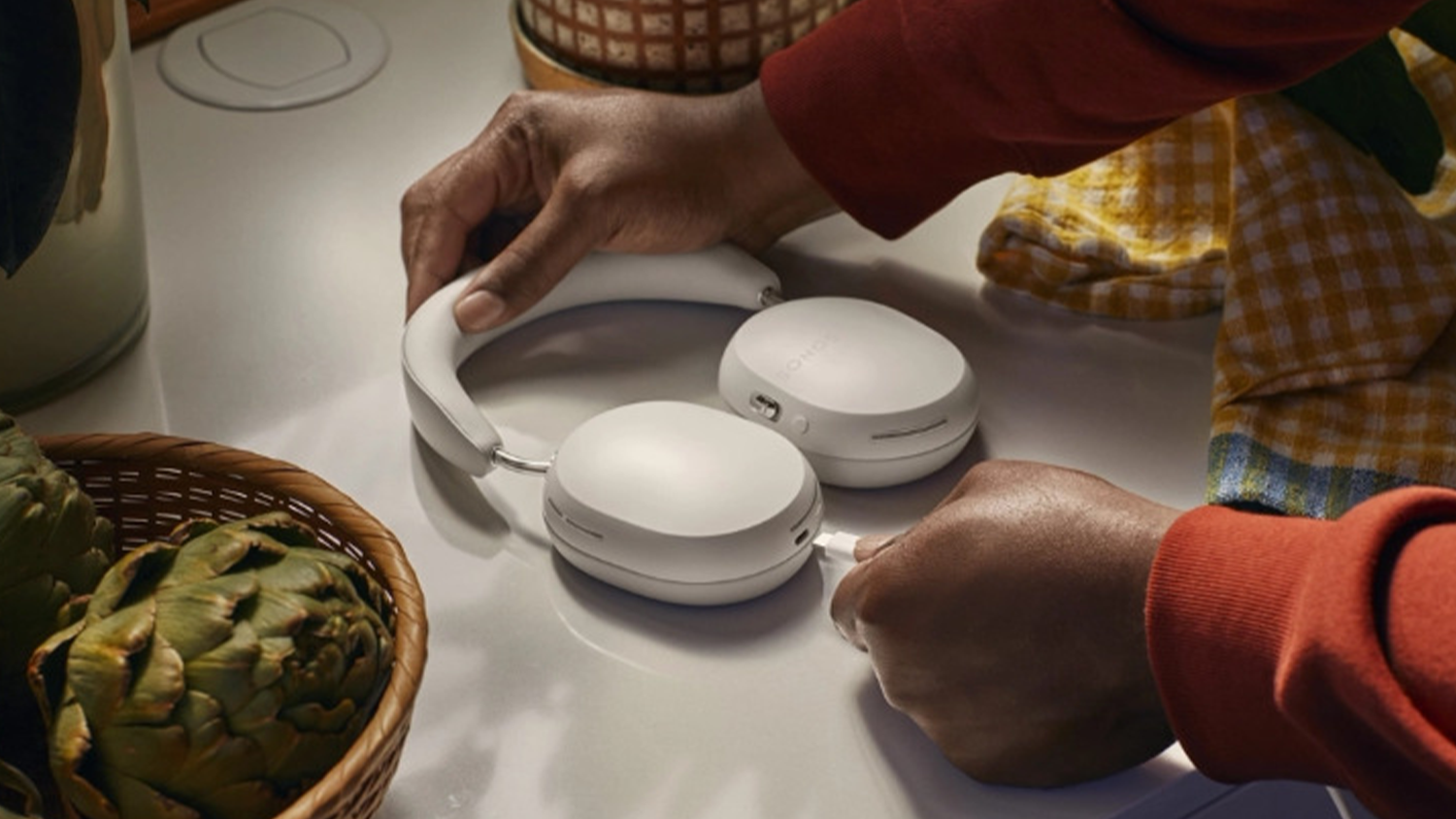 Člověk připojuj&iacute;c&iacute; sluch&aacute;tka Sonos Ace k nab&iacute;ječce