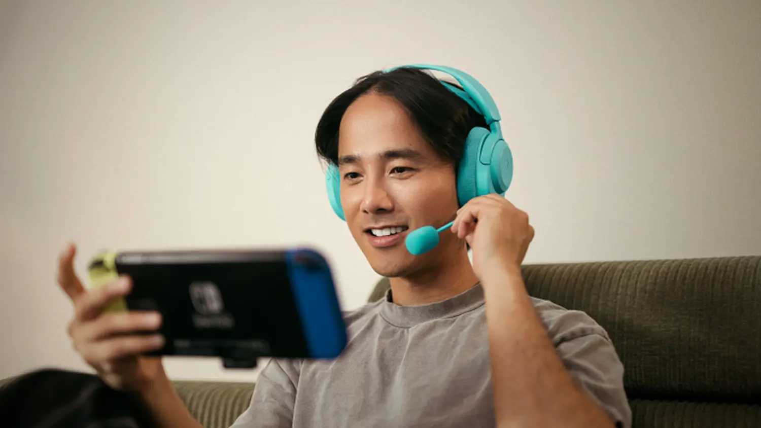 Muž so slúchadlami SteelSeries Arctis Nova 3PW hrajúci na mobile hry