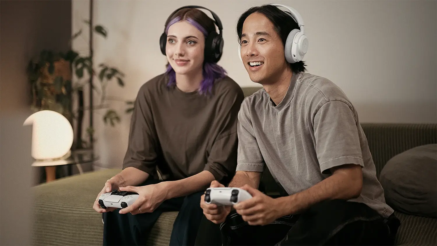 Dvojica so slúchadlami SteelSeries Arctis Nova 3PW hrajúce hry na PlayStation
