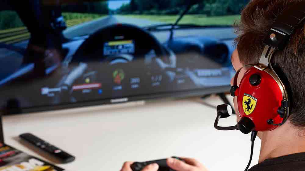 Muž s herními sluchátky Thrustmaster T.Racing Scuderia Ferrari Edition hrající hry_02