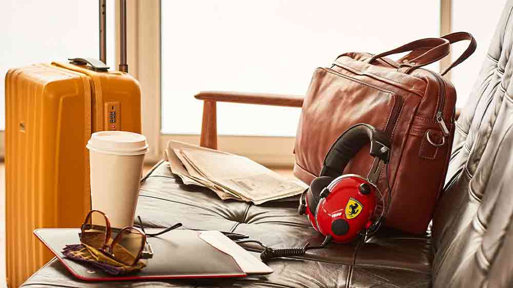 Herní sluchátka Thrustmaster T.Racing Scuderia Ferrari Edition položená na sedačce vedle tašky_03