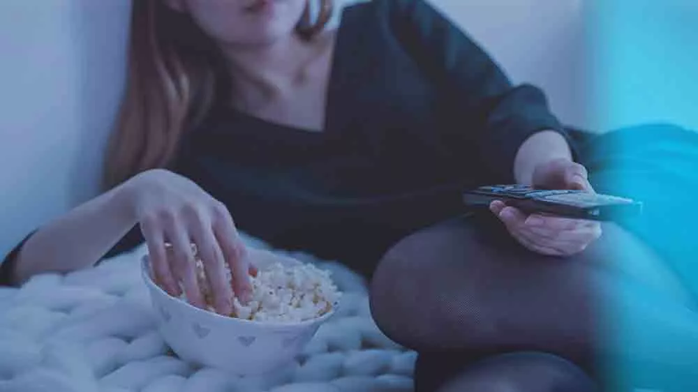 Žena drží ovladač a jí popcorn_04