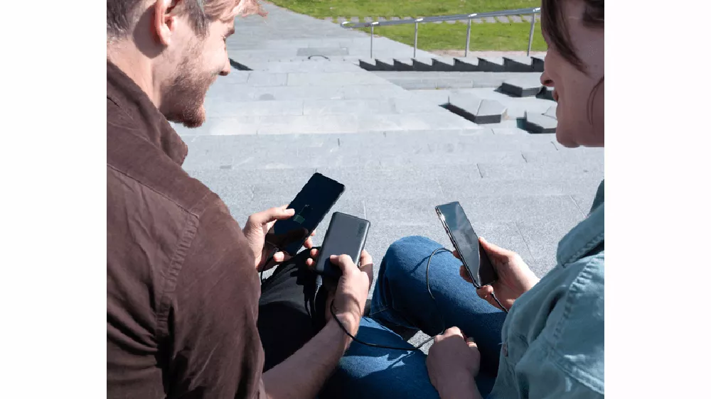 Dva lid&eacute; nab&iacute;jej&iacute;c&iacute; svůj telefonu z powerbanky Trust Primo Ultra Thin 15000 mAh ECO_02