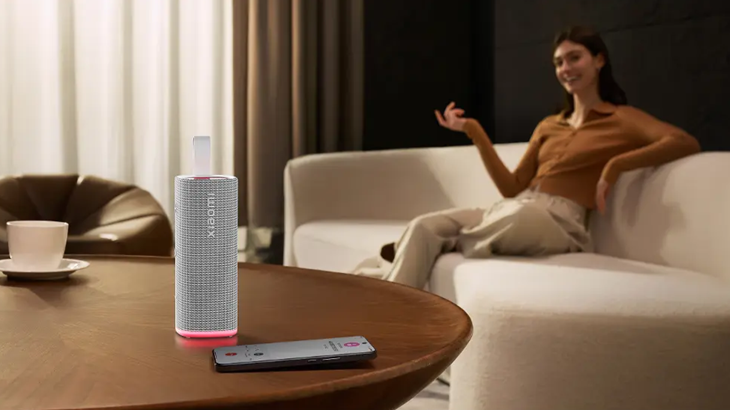 Žena sed&iacute; v ob&yacute;vac&iacute;m pokoji s Xiaomi Sound Play na stole