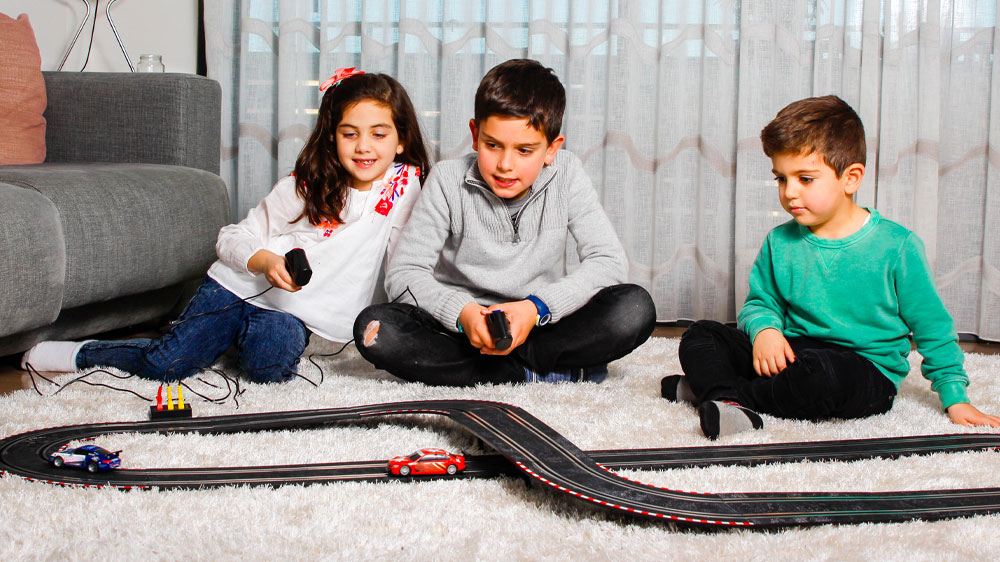 Tři děti hrající si s autodráhou na ovládání_02