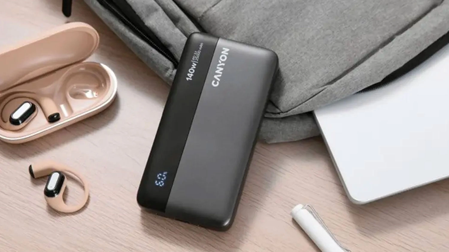 Powerbanka Canyon PB240 25 000 mAh položená na stole vedle sluchátek