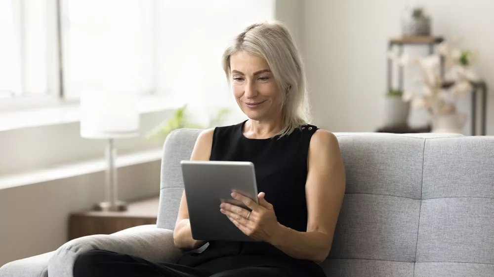 Žena sed&iacute; na pohovce, v rukou m&aacute; tablet_02