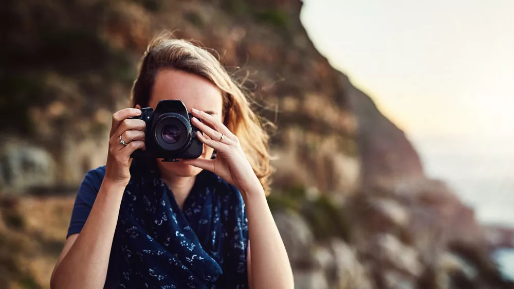 Žena s fotoaparátem na pláži u útesů pořizuje snímky_02