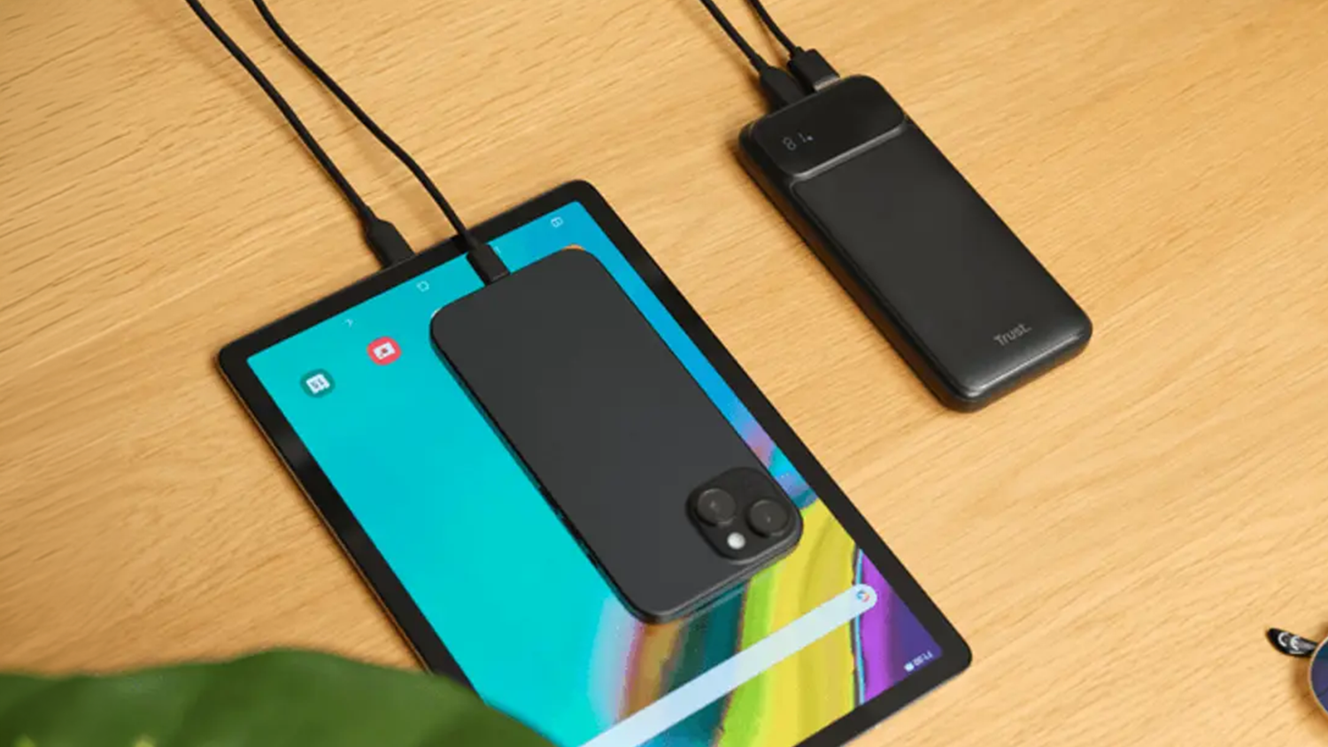 Powerbanka Trust Avala 20 000 mAh na stole při nabíjení více zařízení součaně