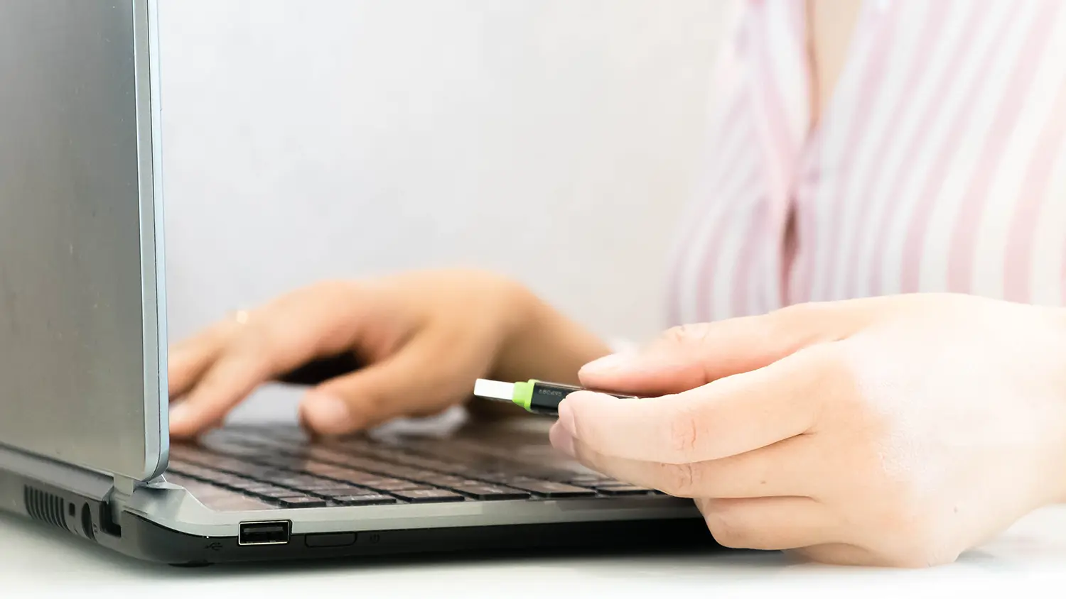 Ruka držící flash disk u notebooku